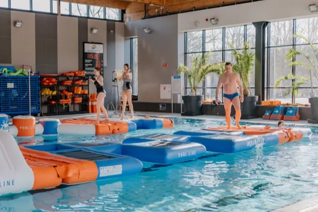 Tor aquafun Pool Line na krytej pływalni, dwie osoby biegną po elemencie Stepstones
